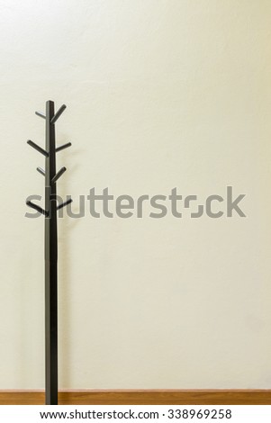 Black wooden coat rack on wall background, space for input text.