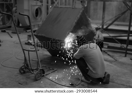The blurry picture of worker welding the steel box in black and white tone , so the customer can type the word in color over this blurry picture.
