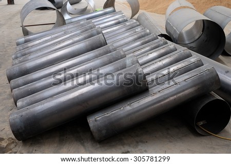 A roll of metal pipeline, wait in construction.  Indoor lighting.
