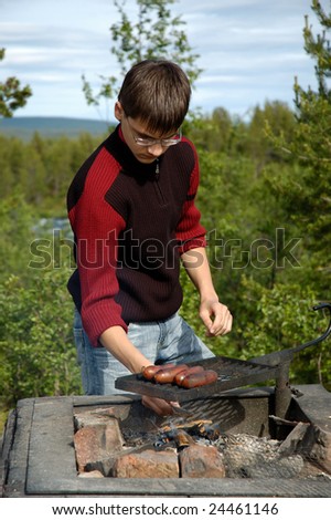 Youth roast sausages on a grill