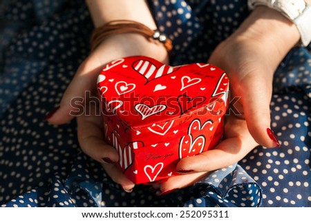 female hands keep box in shape of heart