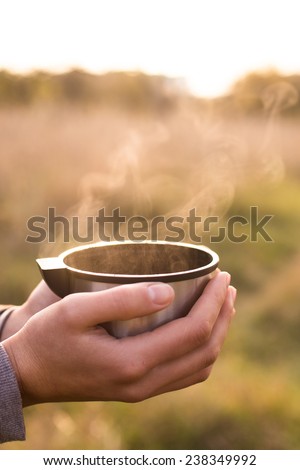Thermos cup in hand on autumn background