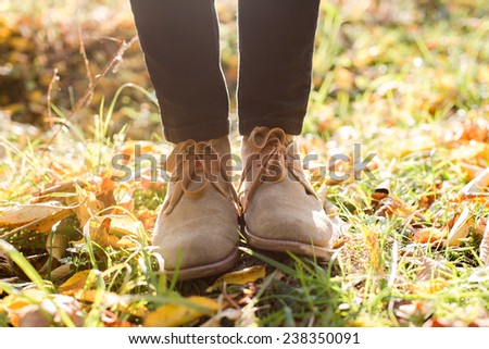Legs in stylish boots on autumn background
