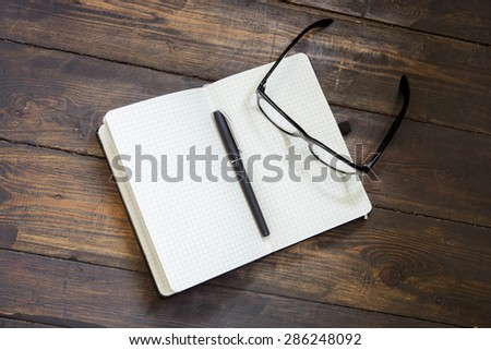 Reading glasses and notepad on wood
