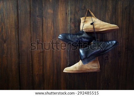Set of old boots hanging on the nail on wooden board