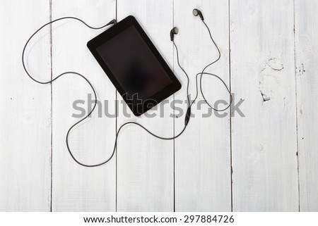 Tablet pc with headphones on wood