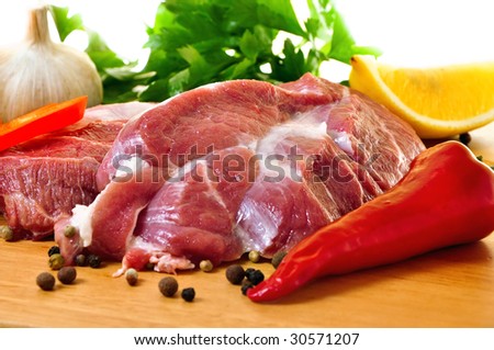 Fresh raw pork on wooden board with vegetables. Isolated on white background.