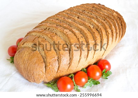 Loaf of sliced cornbread with tomatoes on white background