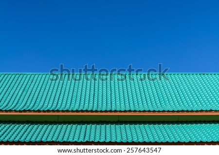 Light green roof tile pattern over blue sky