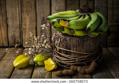 Banana on timber, little dry flower, star apple and tamarind on wood table background