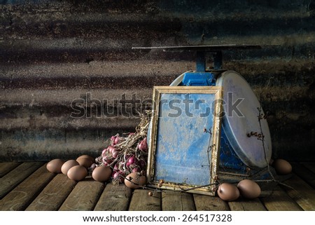 Still life with old photo frame, egg, onion and old blue scales on wood table and rusty steel plate background