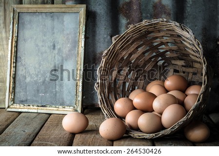 Still life with eggs in bamboo basket on wood table with rusty steel plate background