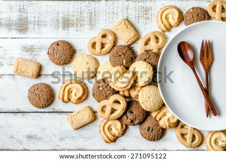 Butter and chocolate chip cookies with wooden spoon and white ceramic dish on old wood table