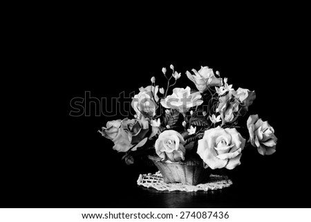 Still life with black and white clay roses in basket, low key image