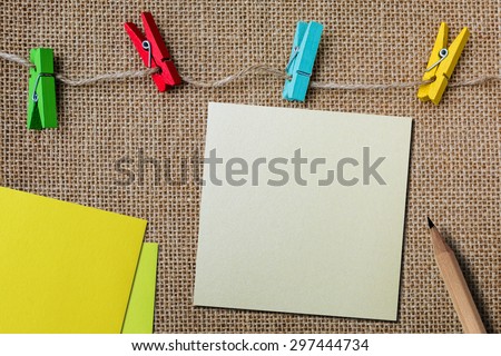 Note paper with pencil on sackcloth texture background with colorful wood clips