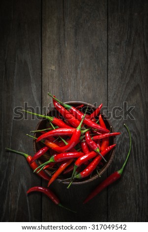 Red Hot Chili Peppers in wooden bowl on old wooden background, Overhead view of chili pepper on wood background, Dark food photography with red chili