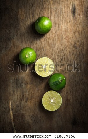 Organic lime on rustic wood board background, Still life photography with lime on wood board background, The art of food photography with limes on rustic wood board background