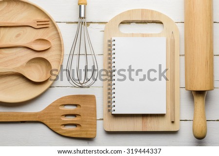 Notebook to write the list of menu and wooden kitchen utensils on clean wood board background