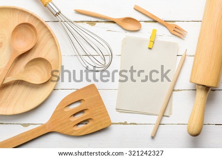 Notebook to write the list of menu and wooden kitchen utensils on wood board background