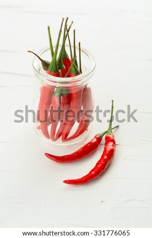 Red Hot Chili Peppers in glass bottle on white stone plate background, Still life photography with chili peppers