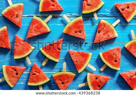 Watermelon slice popsicles on a blue rustic wood background, Popular summer fruit with yummy watermelon, Flat lay photography of Watermelon slice popsicles