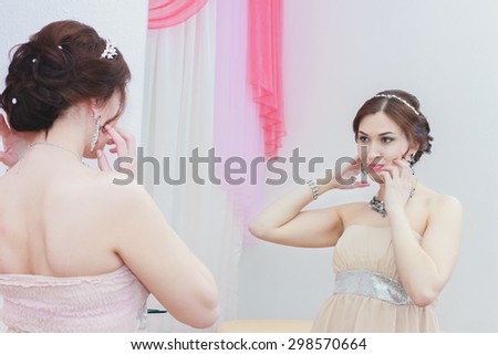 beautiful girl with sparkling jewelry and perfect skin is waiting for her wedding and looking in the mirror