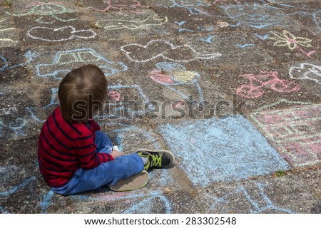 Kid sitting on floor drawing with chalk