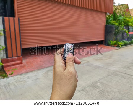 Hand holding the remote to open the sliding door.Remote control door.Electrical door.Automatic door.