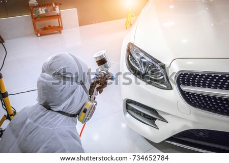 Staff wear Chemical protective clothing at work.Car Care Business. Automobile industry. Car wash and coating business with ceramic coating.Spraying the varnish to the car.