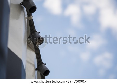 Light Bulb hangs on the string on top of container box with sky for the background