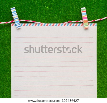 Letter paper with colorful clips on green background