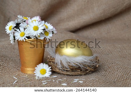 Golden egg in nest and daisies on canvas