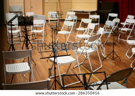 Empty music stand and chairs on stage. Selective focus on music stand.