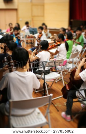 Blurred image of students practicing in school string orchestra