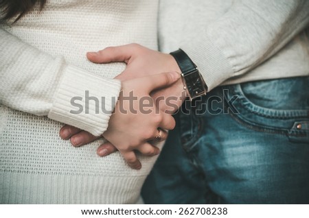 Portrait image of a happy young couple cradling and admiring the woman\'s pregnant belly.