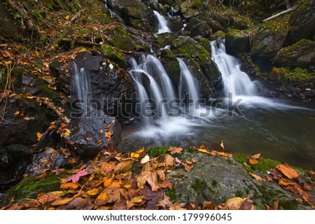Autumn landscape with a waterfall on the creek taiga.