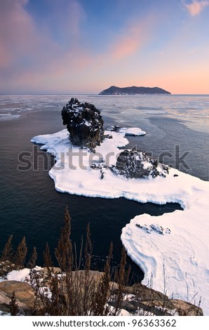 Winter landscape with a lone rock on the shore of the winter sea. Japan Sea.