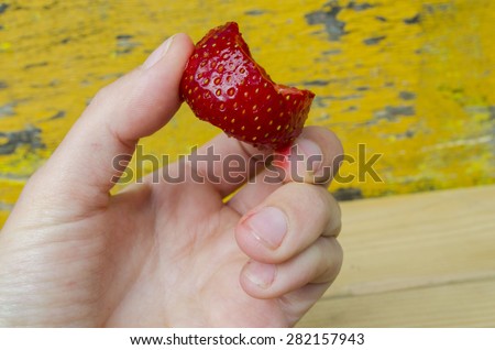 Half eaten strawberry in the hand