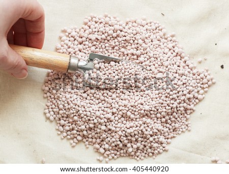 Garden background with mineral fertilizers balls. Complex mineral fertilizer with sodium, phosphorus for flowers, plant, tree. Backdrop with small garden tools shovel. Place for text.