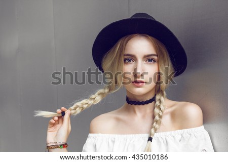 Pigtails. Close up of beautiful young blonde woman with black hat. Her hair is tied in two big ponytails. Around neck she has black choker.\
Professional make-up, hair style and styling.
