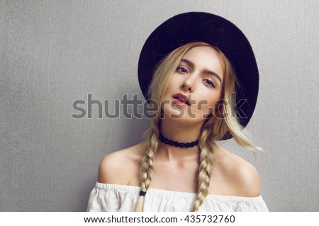 Pigtails. Close up of beautiful young blonde woman with black hat. Her hair is tied in two big ponytails. Around neck she has black choker.\
Professional make-up, hair style and styling.