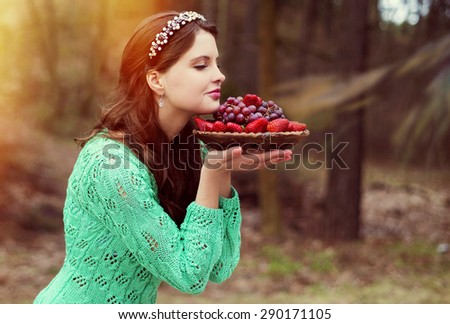 The woman in the wood, inhales aroma of fresh strawberry and grapes