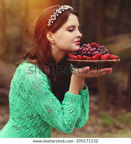 The woman in the wood, inhales aroma of fresh strawberry and grapes