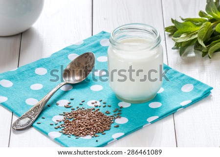 yogurt with flax seeds and old silver spoon on white wooden table