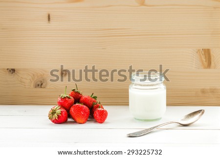 yogurt with old silver spoon and strawberry  on white table at wooden background