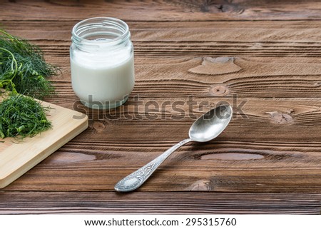 yogurt  in glass jar with old silver spoon and dill on wooden table at country style
