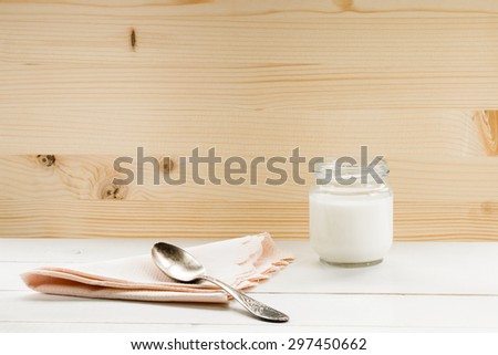yogurt with old silver spoon on white table at wooden background