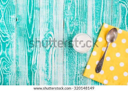 yogurt in jar with old silver spoon on yellow napkin at white polka dots  on turquoise colored wooden table. top view. copy space, free space for your text.