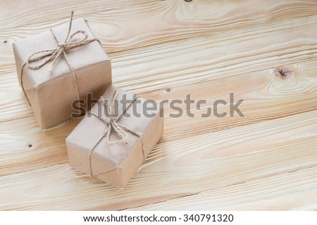 christmas gifts packaged in kraft paper,  jute rope constricted on wooden background. top view, free space for text