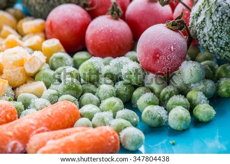 frozen vegetables: broccoli, cherry tomatoes, corn, pea, carrot on blue plate